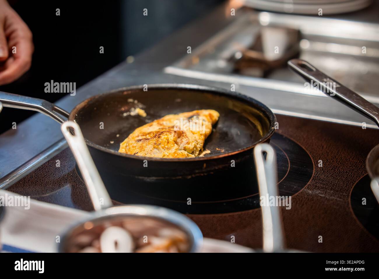 Omelet in nonstick skillet on induction cooktop in Zermatt kitchen Stock Photo