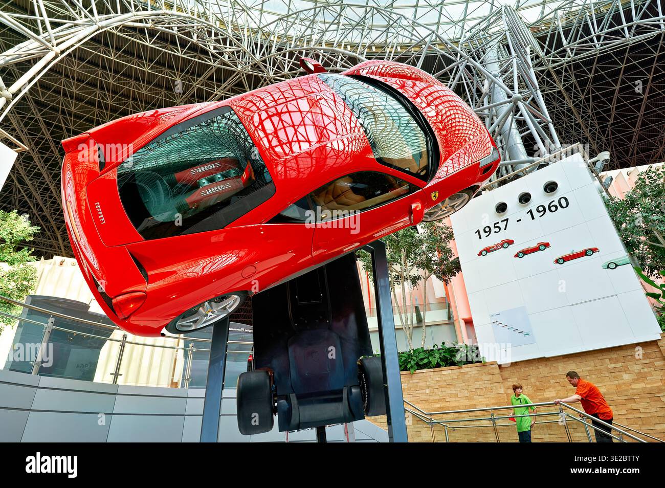 AVisitors at Ferrari World in Abu Dhabi see a large red racing car on display inside the amusement park. Excitement fills the air as guests explore. Stock Photo