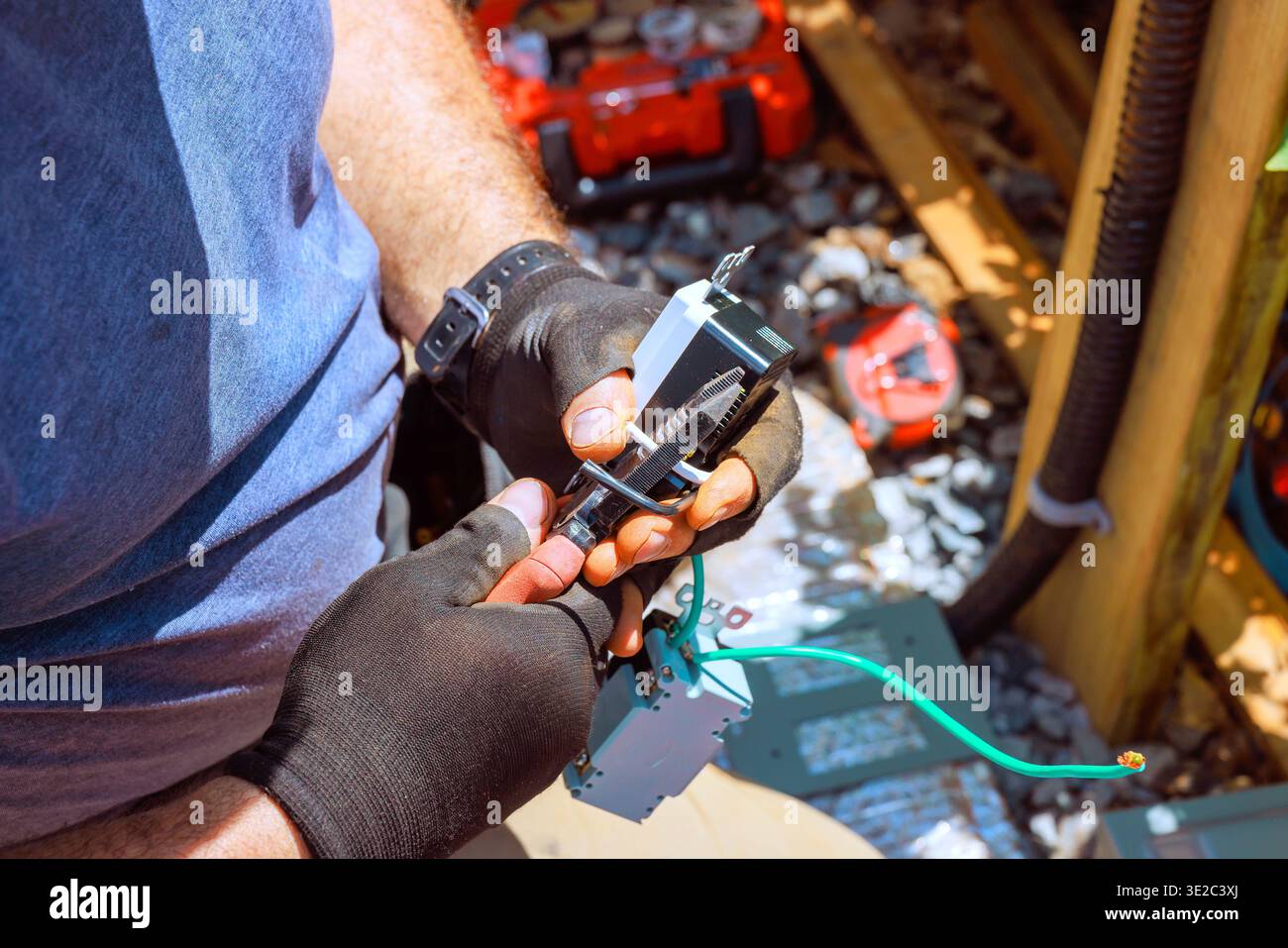 Worker focuses on connecting wires while using tools at construction area Stock Photo