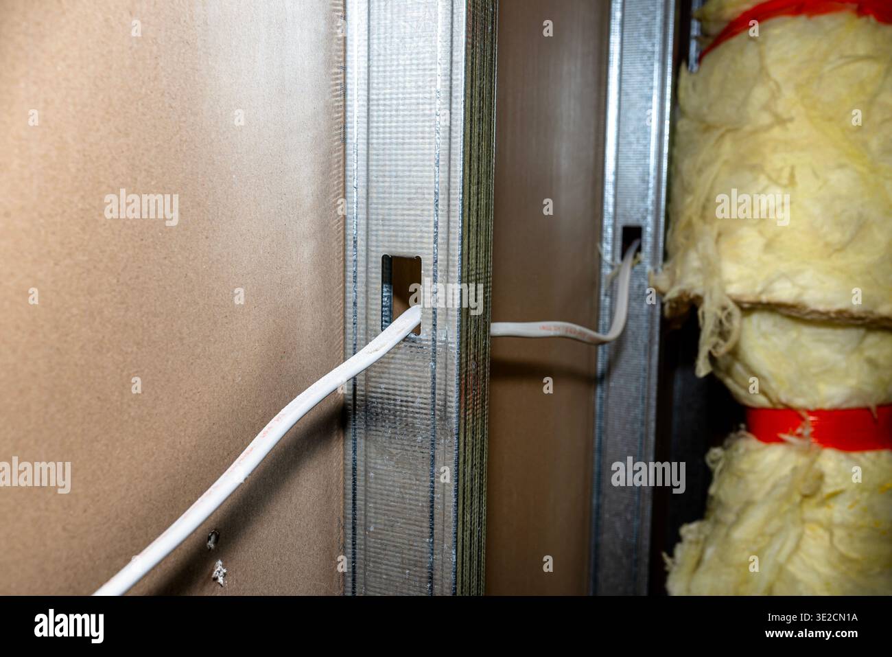 Builders installing metal studs, electrical cables, and insulation during interior construction Stock Photo