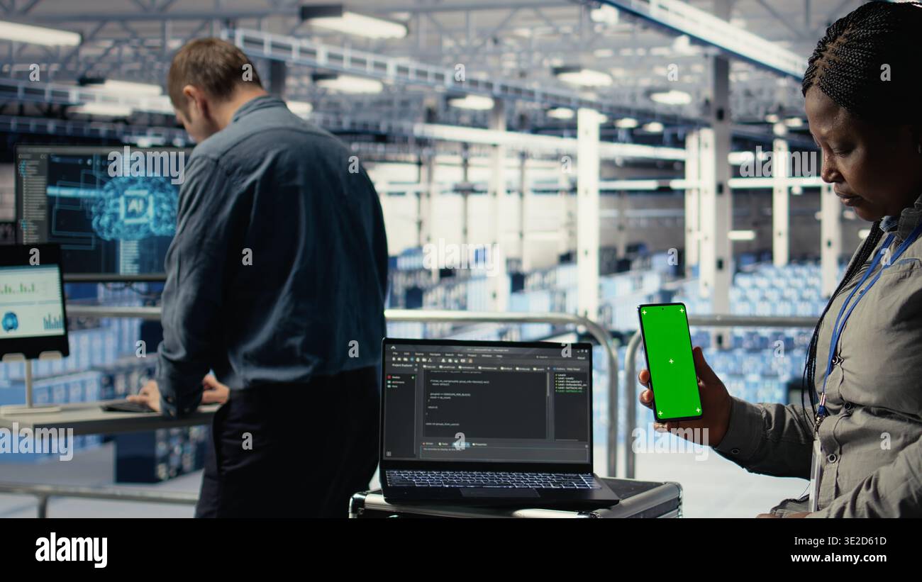 Engineer using isolated screen smartphone in server room while optimizing deep learning systems handling tasks. Data center worker uses chroma key mobile phone, adjusting AI model parameters, camera A Stock Photo