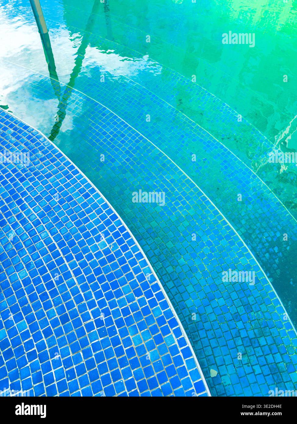 The scene shows blue tile steps leading into a pool filled with clear ...