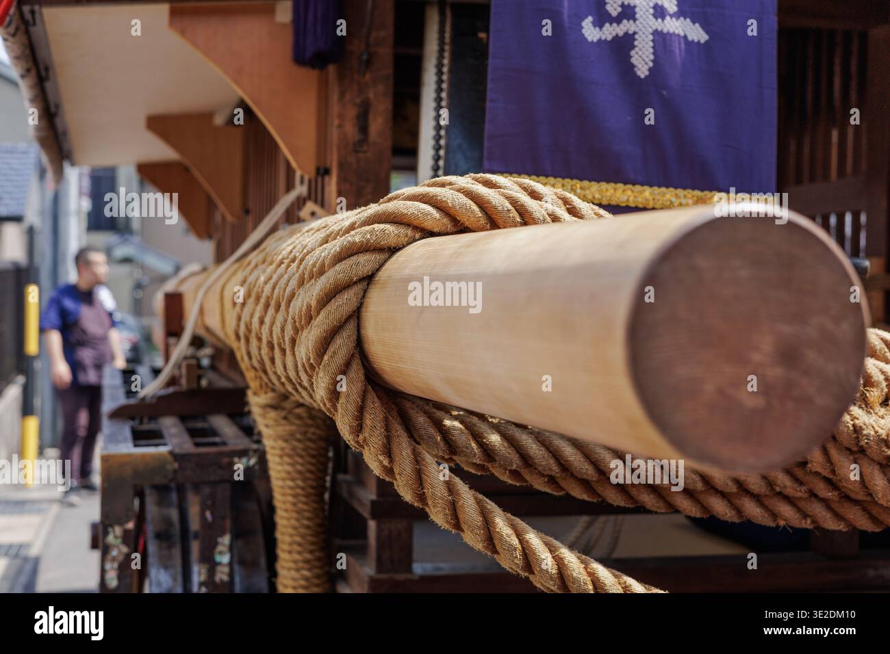 Side view of Japanese Omikoshi festival float, showcasing thick pulling rope tightly coiled around smooth wooden hoisting beam for carriers shoulders. Stock Photo