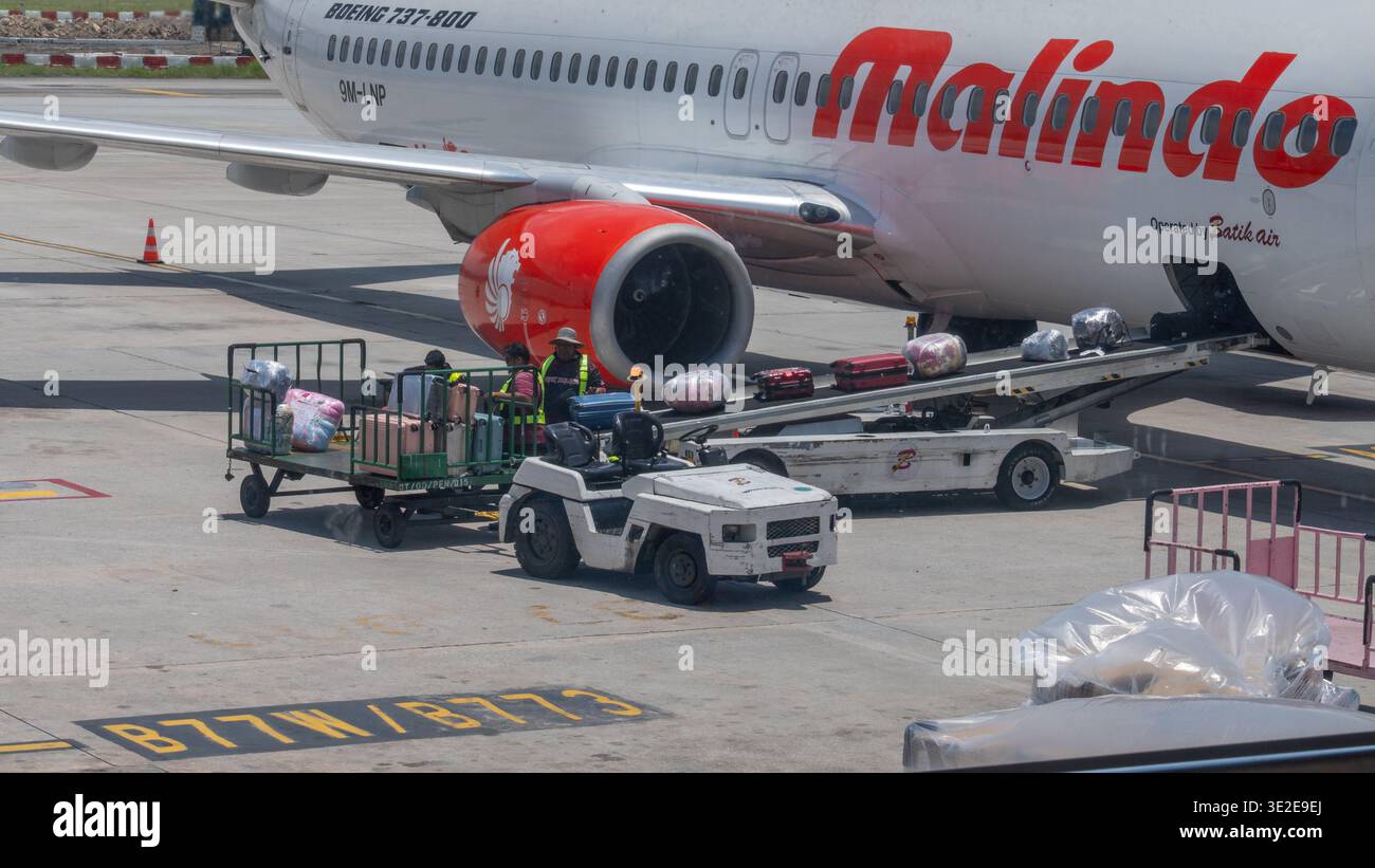 Ground crew loading baggage onto a Malindo Air Boeing 737-800 aircraft ...