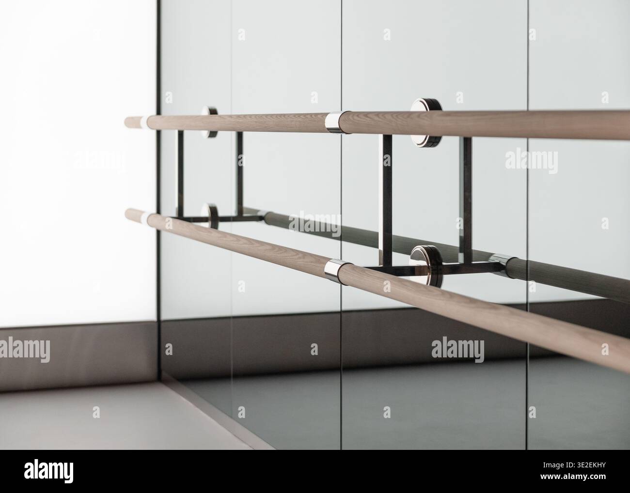 Ballet barre with wood rails and chrome mounts on mirrored wall. Dance ...