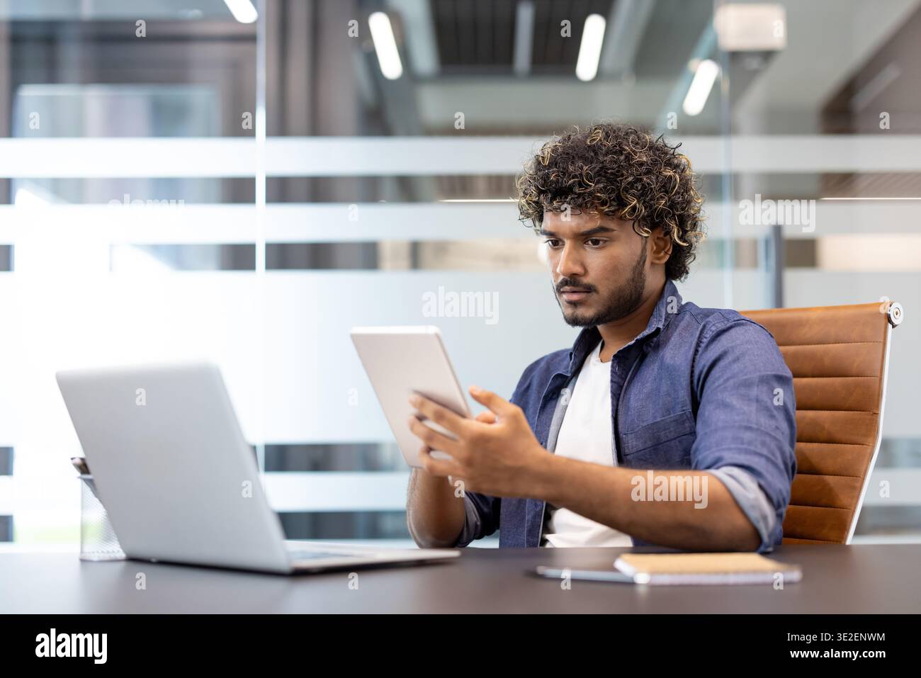 Muslim young man is working in the office with a laptop and using a tablet. Stock Photo