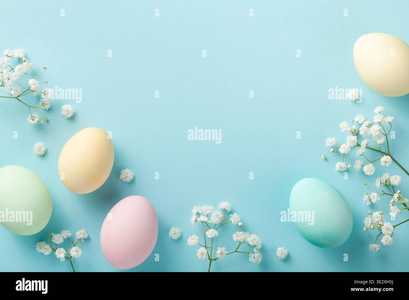 Pastel Easter eggs on blue background top view. Flat lay style. Stock Photo