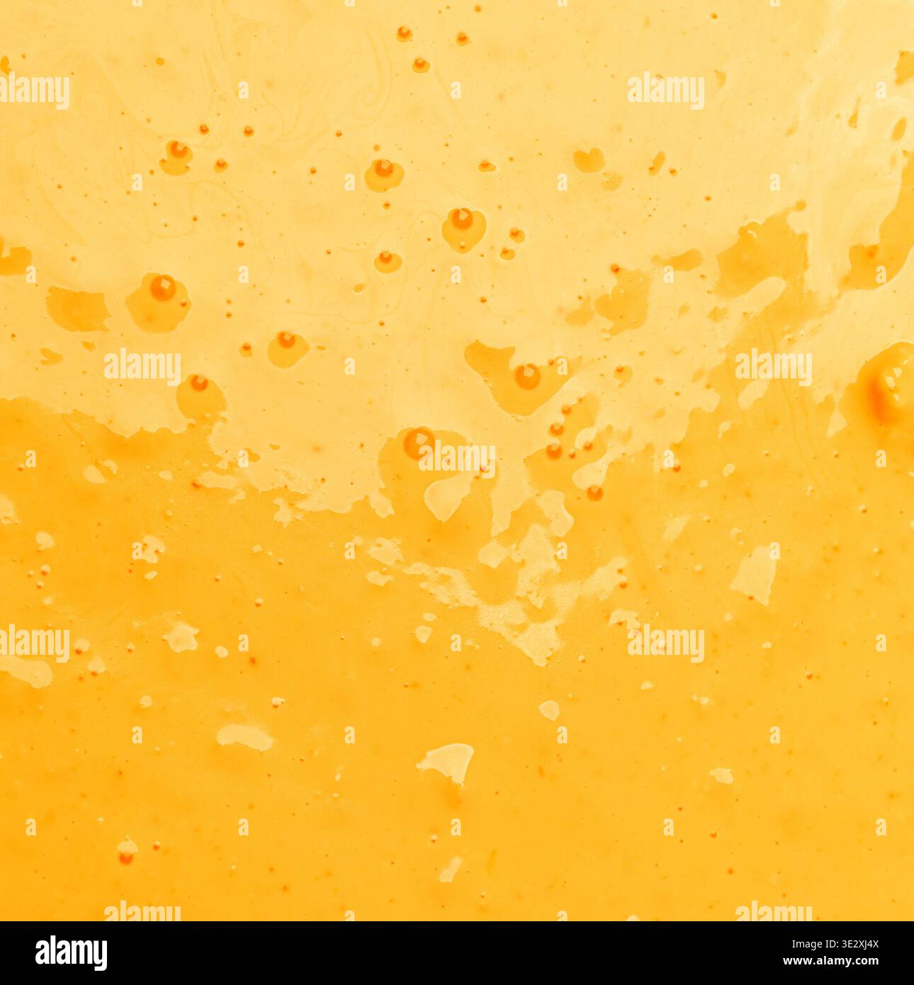 Abstract background showing bright yellow orange liquid with tiny bubbles and splatters Stock Photo