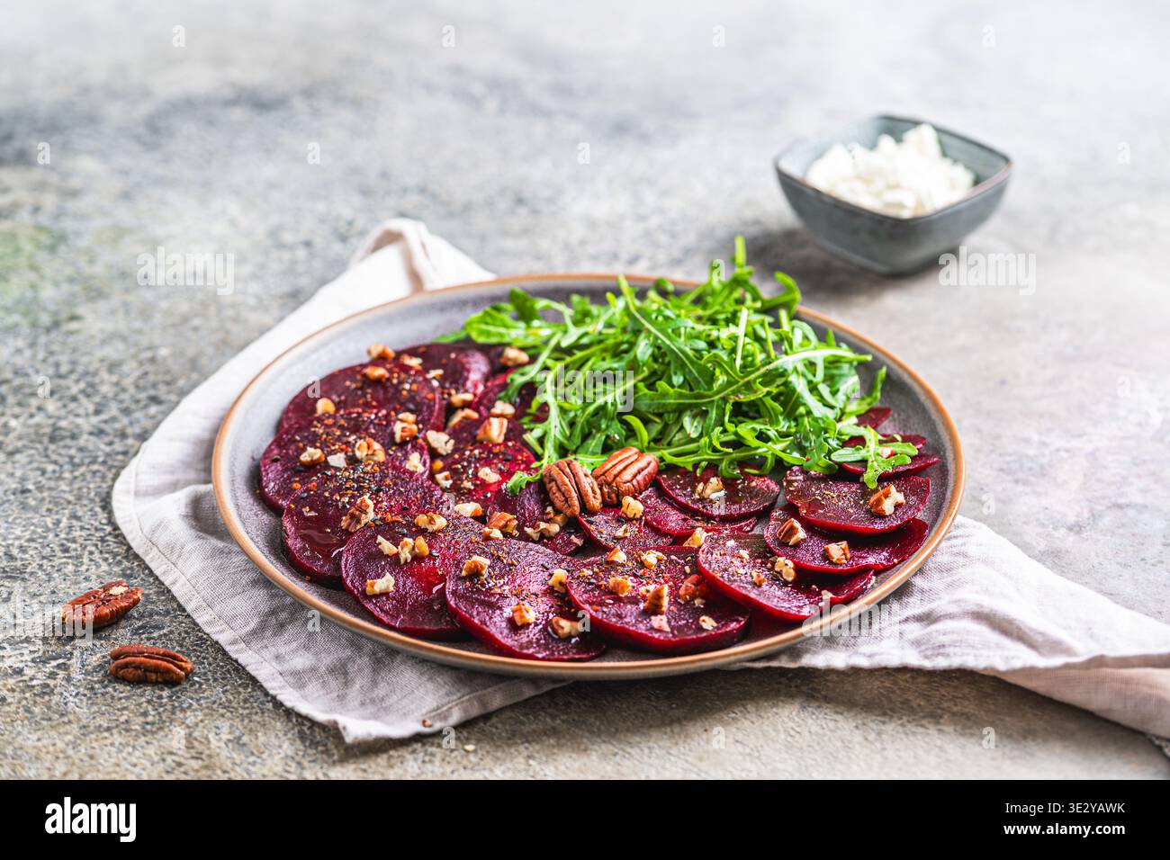 Beetroot carpaccio with walnuts and arugula salat on gray rustic background, copy space Stock Photo