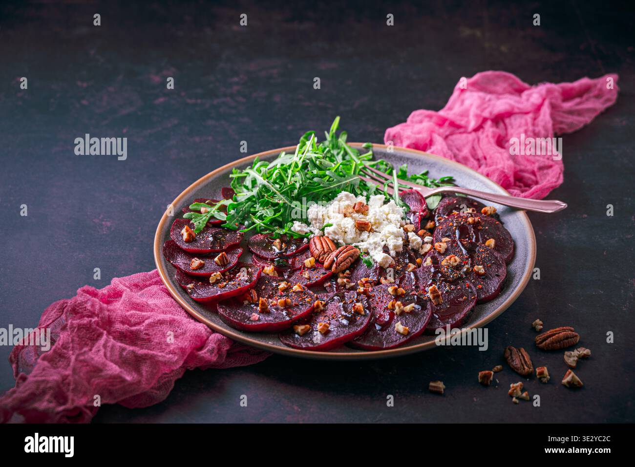 Beetroot carpaccio with balsamic glaze, walnuts, sheep cheese and rocket salat on dark background, copy space Stock Photo