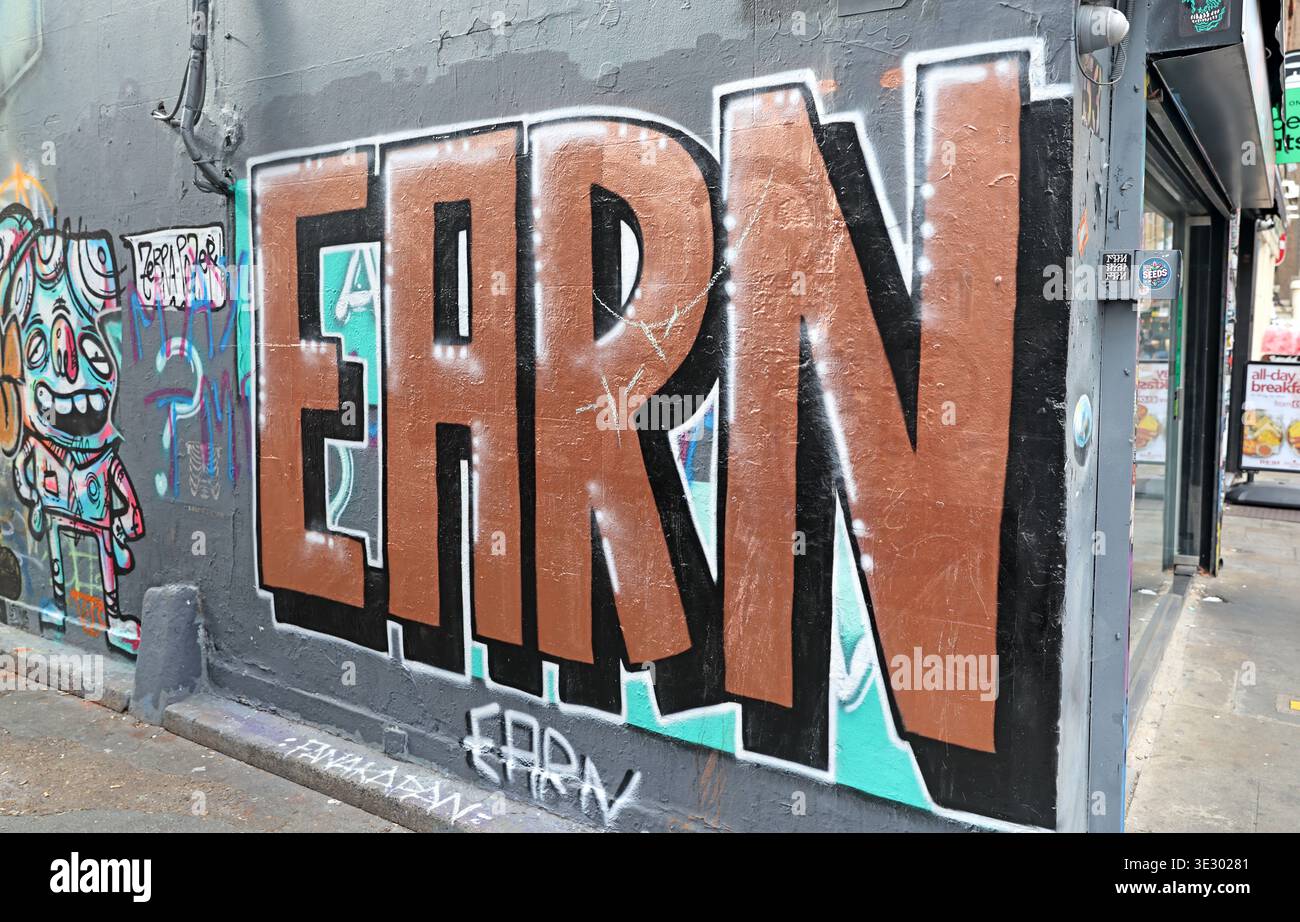 Large graffiti word 'EARN' painted on a wall in Brick Lane, east London, amid the area's dense street-art scene. Stock Photo