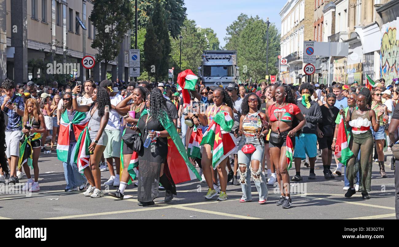 Surinamese flag-waving revellers join the colourful Notting Hill Carnival parade in west London before the 2026 60th anniversary year. Stock Photo