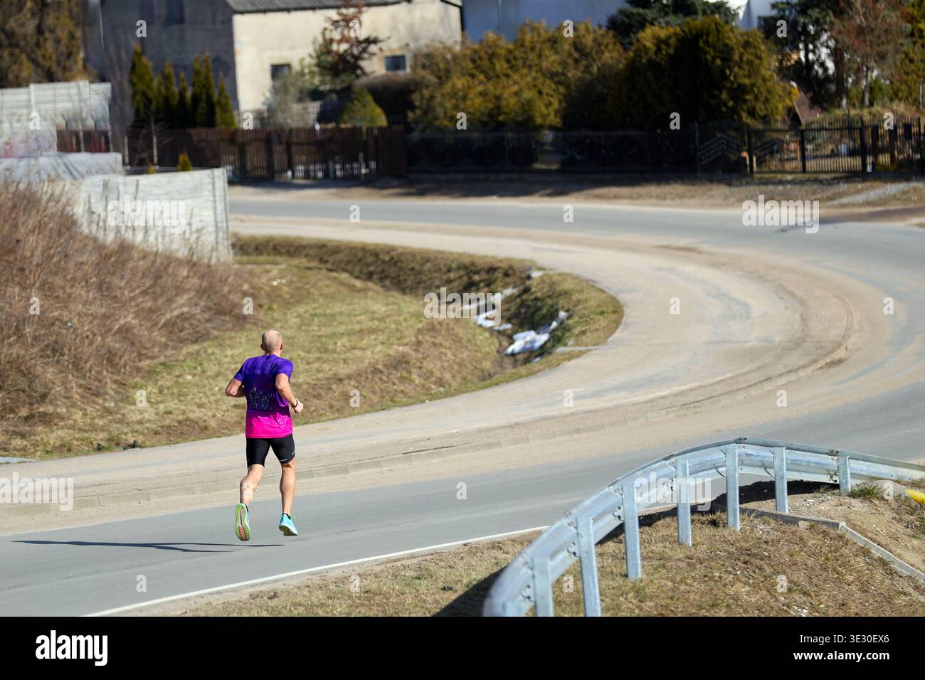 man Running on a Winding Road in a Rural Landscape outdoors Stock Photo