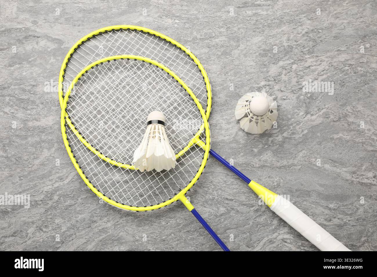 Badminton rackets and shuttlecocks on grey table, top view Stock Photo