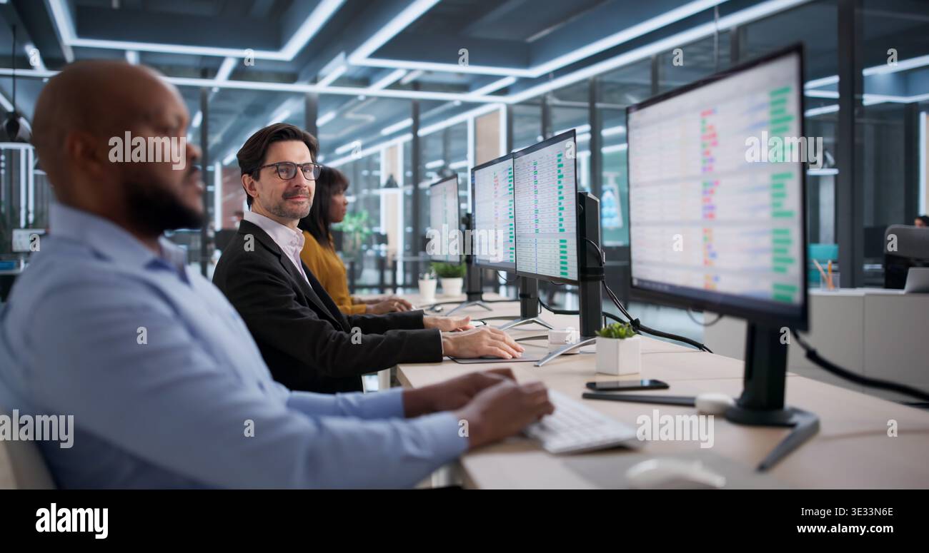 Diverse Office Team Happily Using Spreadsheets At Desks, Working Together. Young Woman Analyst Studying Reports Stock Photo