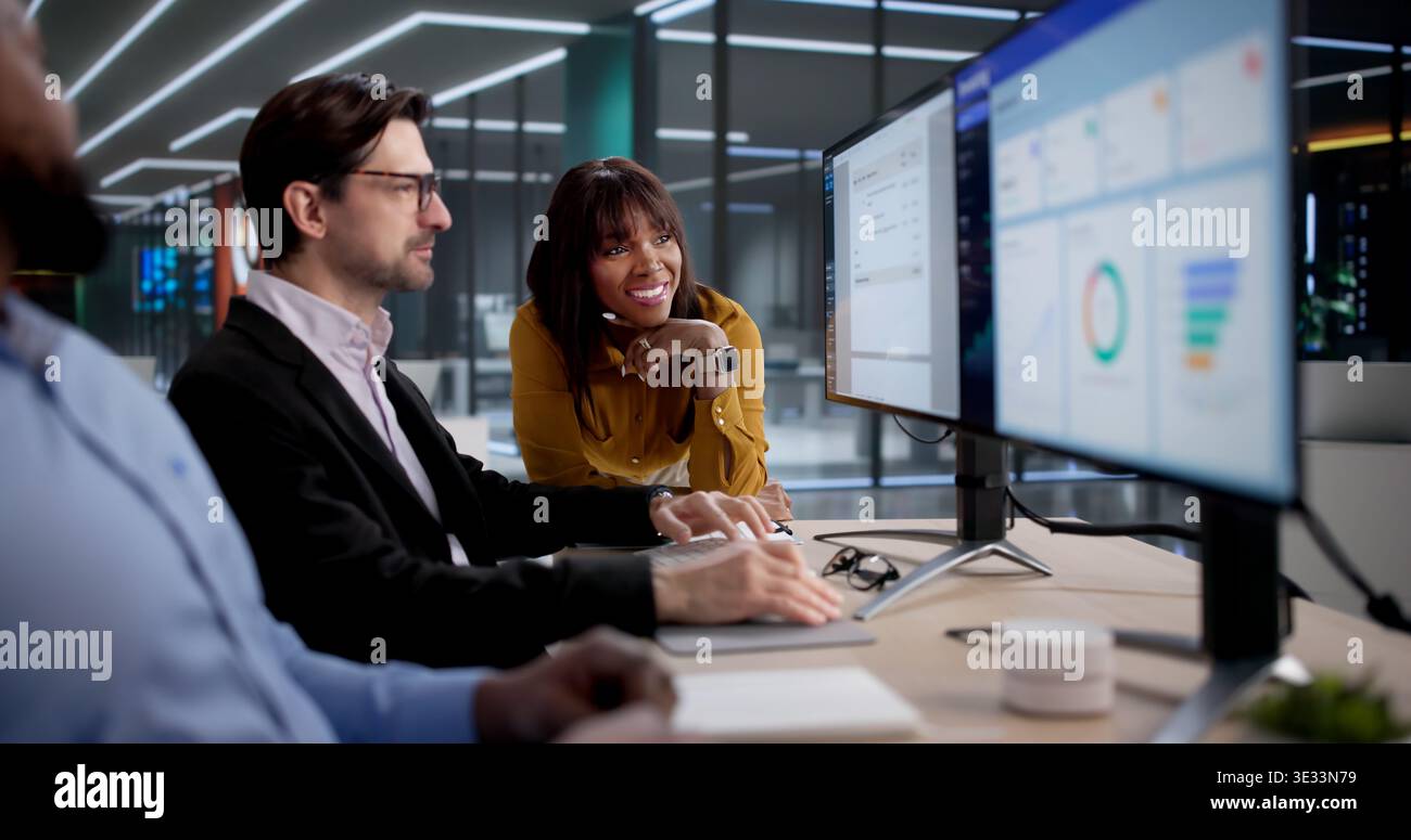 Diverse Team Of Office Workers Using Computers To Process Invoices Efficiently. The Person Could Be Coding Software Stock Photo