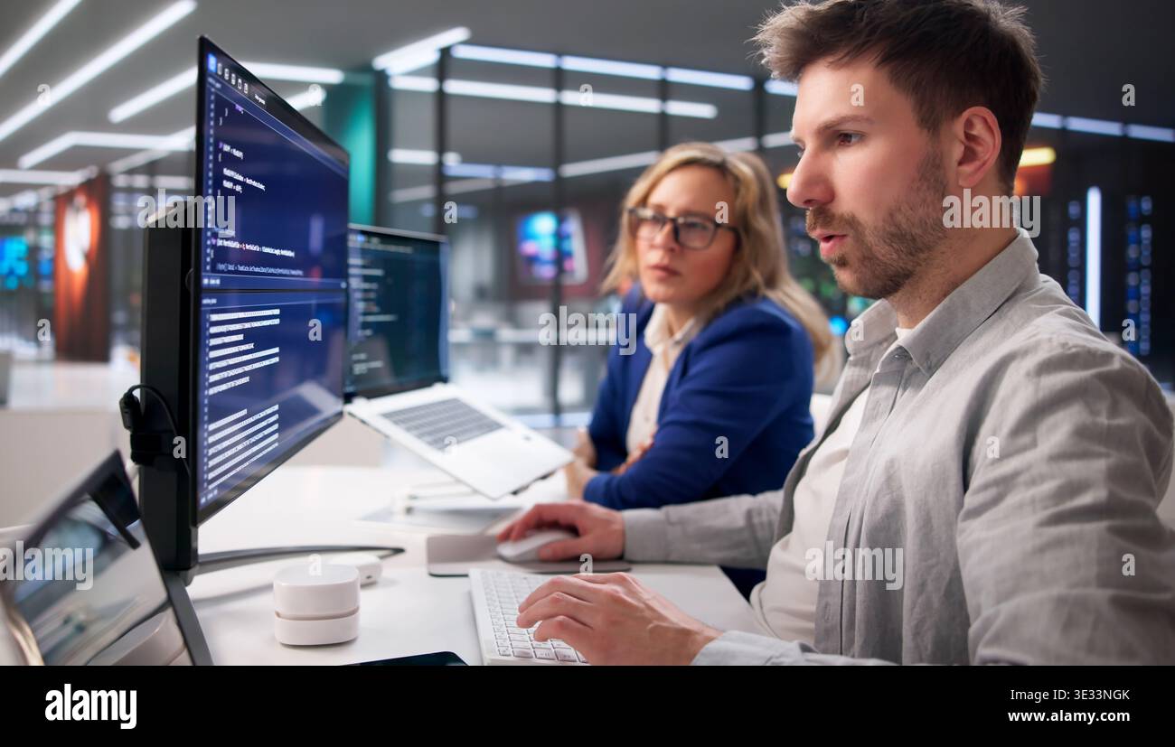 Tech Professionals Collaborating On Code In Contemporary Workspace Stock Photo