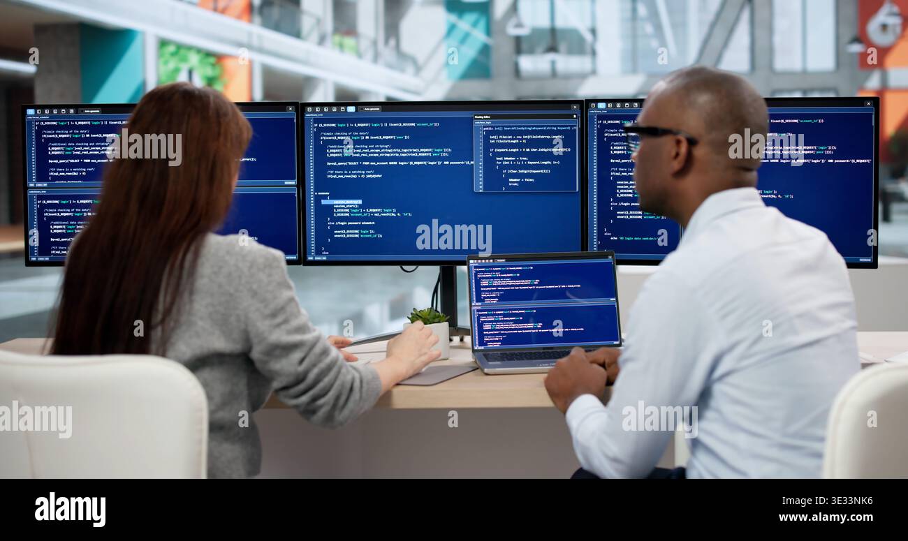 Focused Young Programmers Coding On Computers, Collaborating In Office Meeting. Agile Software Developers Analyze Data Stock Photo