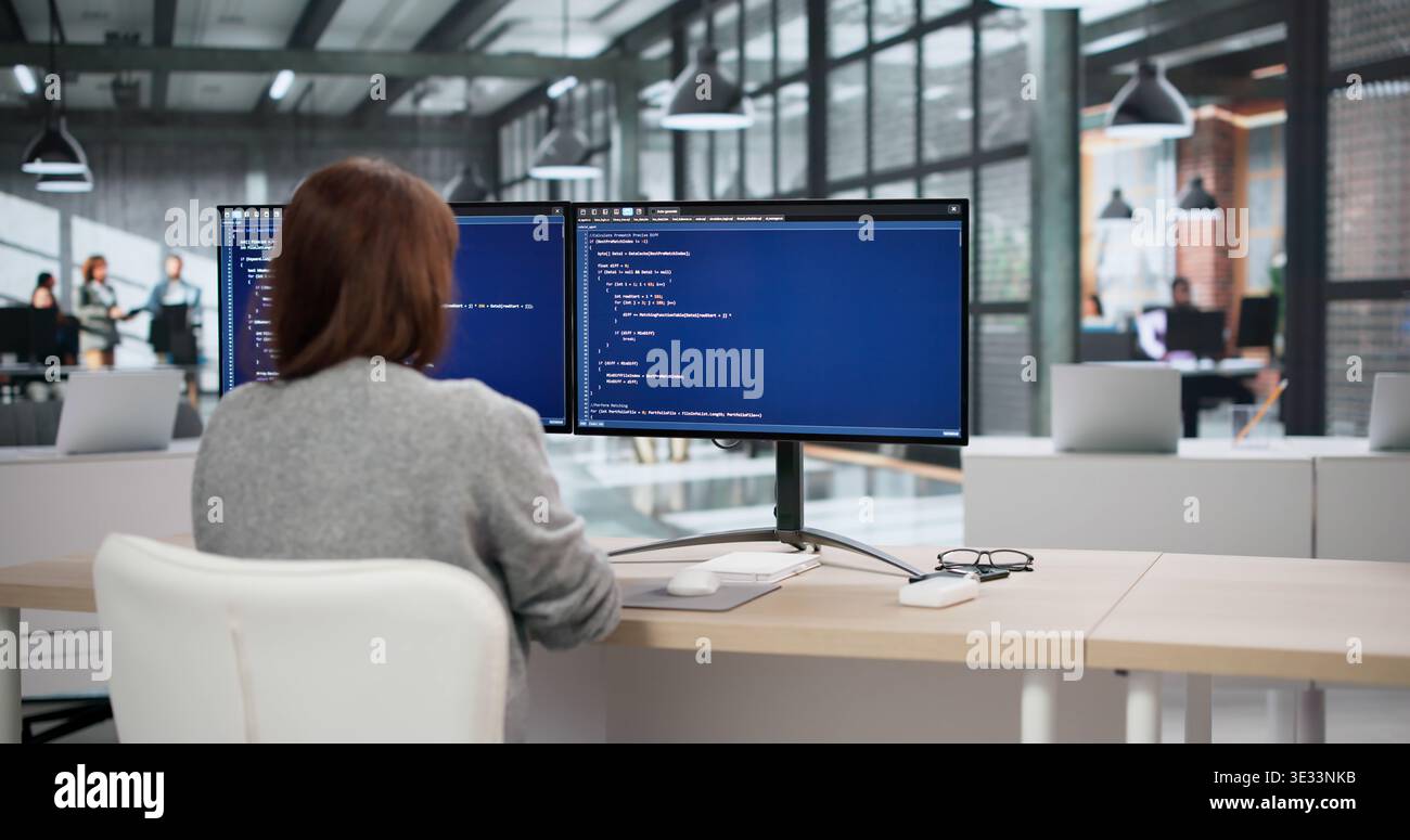 Two Software Developers Coding On Computers While An Accountant Reviews Billing Data Nearby Stock Photo