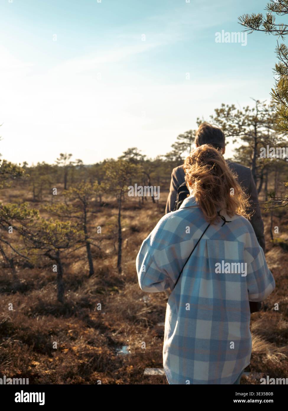 Rear view of couple in golden backlight gazing over open Kakerdaja bog Estonia in spring Stock Photo