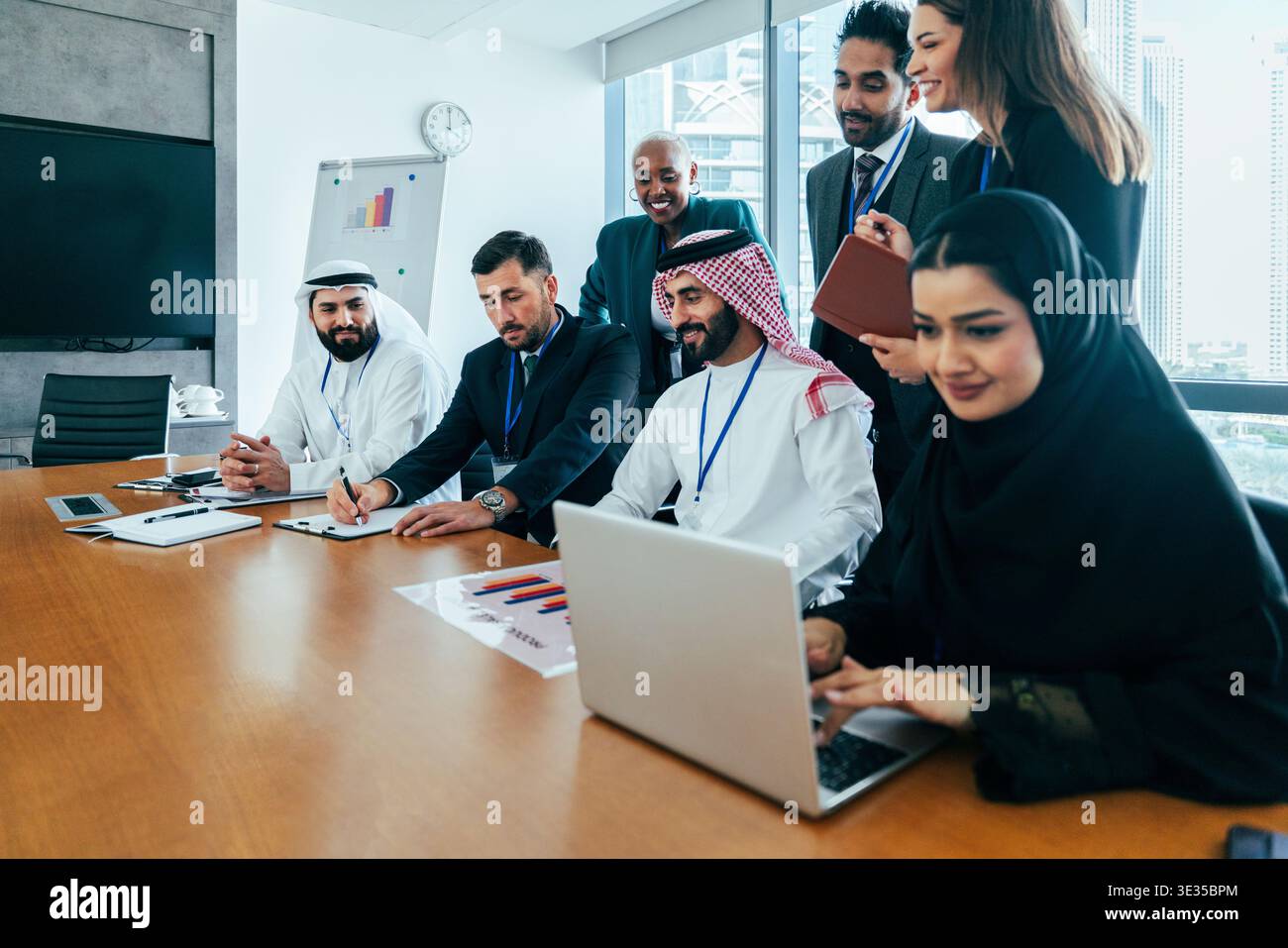 Multiethnic business team collaborating during a corporate meeting in a modern office, using a laptop and discussing strategy for international busine Stock Photo