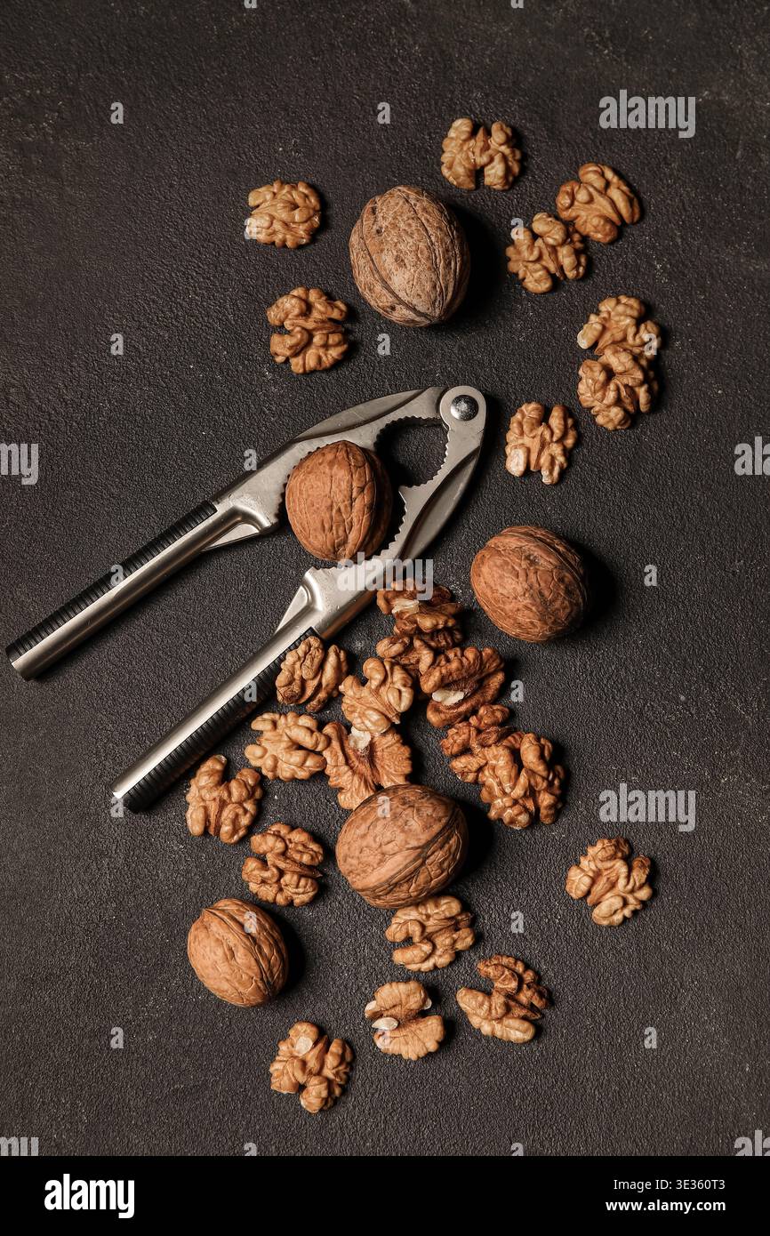Tasty walnuts and nutcracker on black background Stock Photo