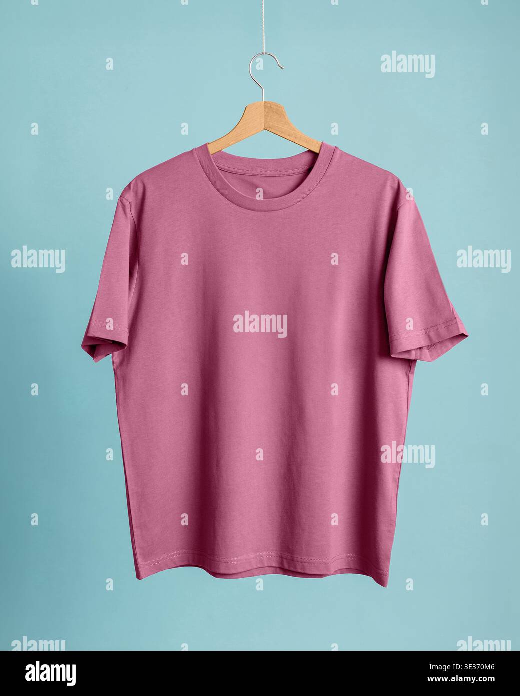 Mauve orchid pink oversize t-shirt on wooden hanger, teal blue background. Plain blank tee. Eye-catching pink-teal chromatic contrast highly sought in Stock Photo