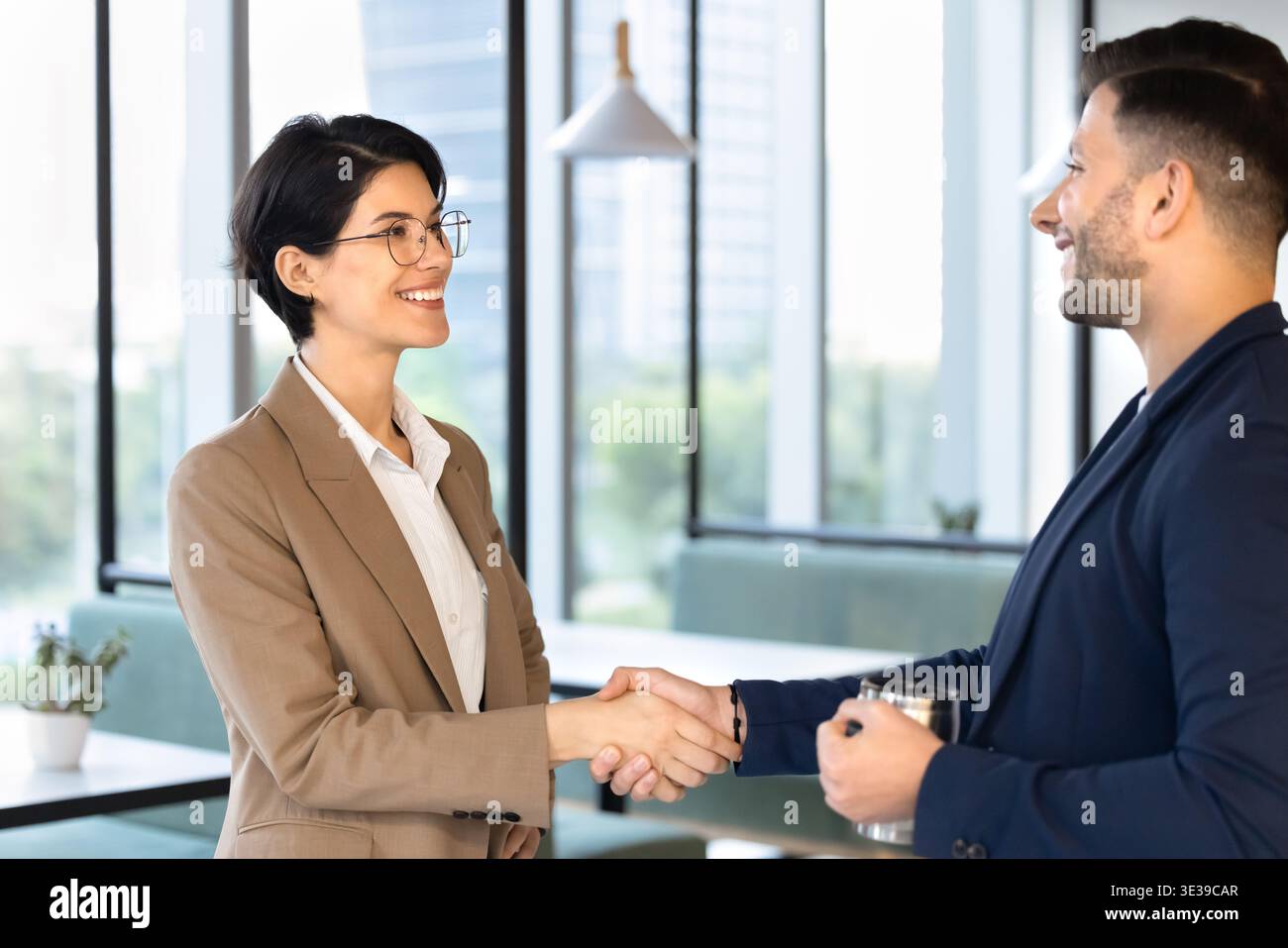 Two smiling multiethnic coworkers greeting during work break Stock Photo