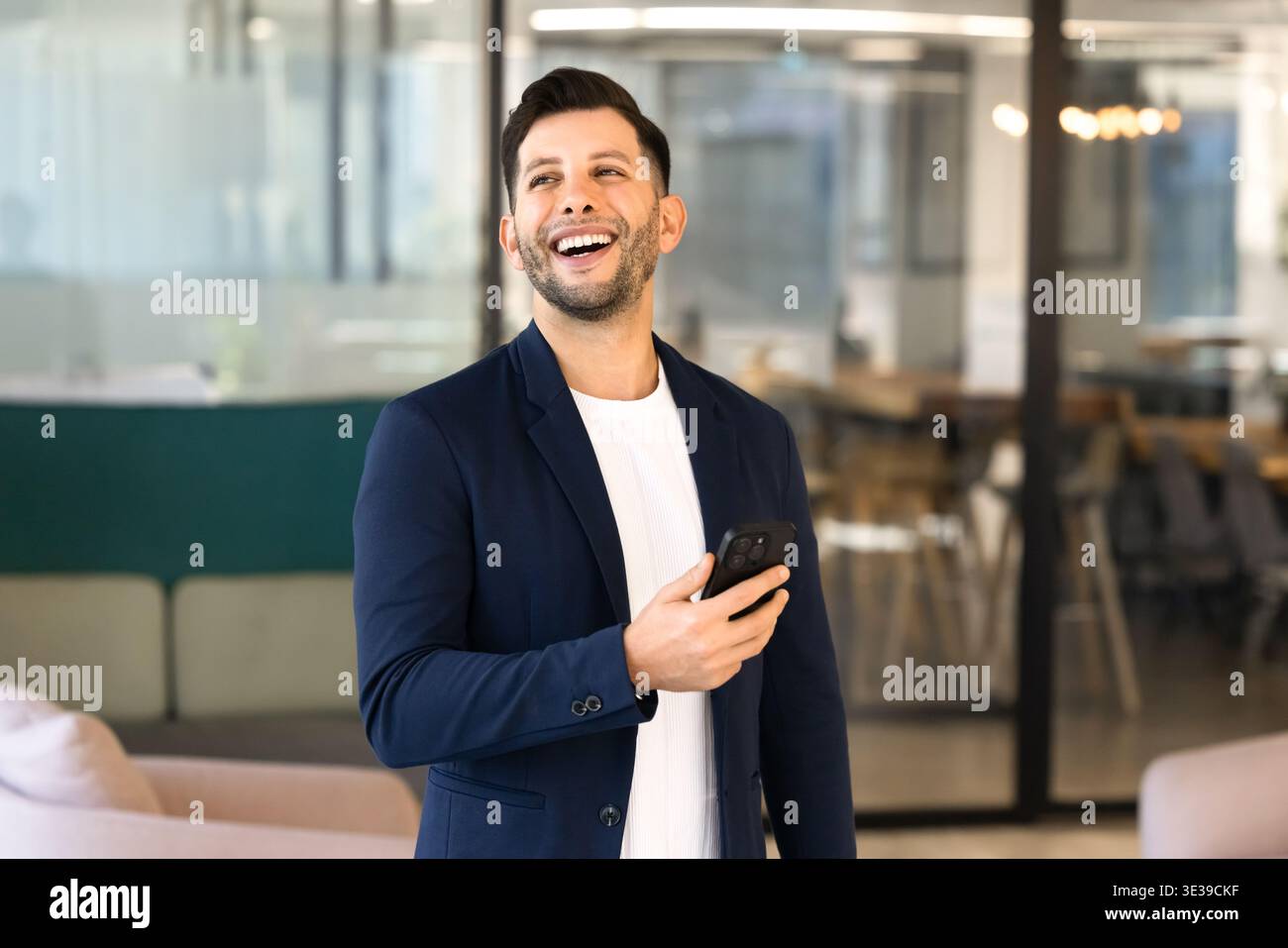 Middle Eastern businessman laughs on received message on smartphone Stock Photo