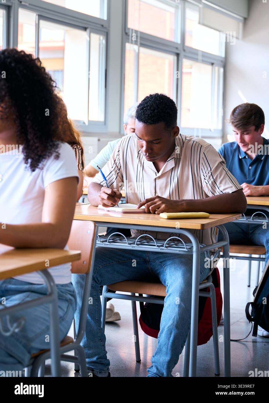 Focused students using laptop and writing in classroom Stock Photo