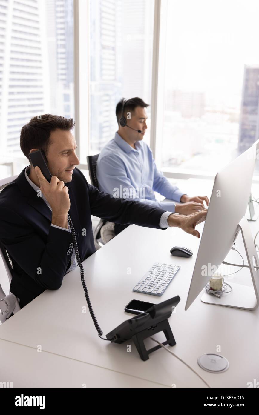 Busy diverse client support operators managing customer calls by computers Stock Photo