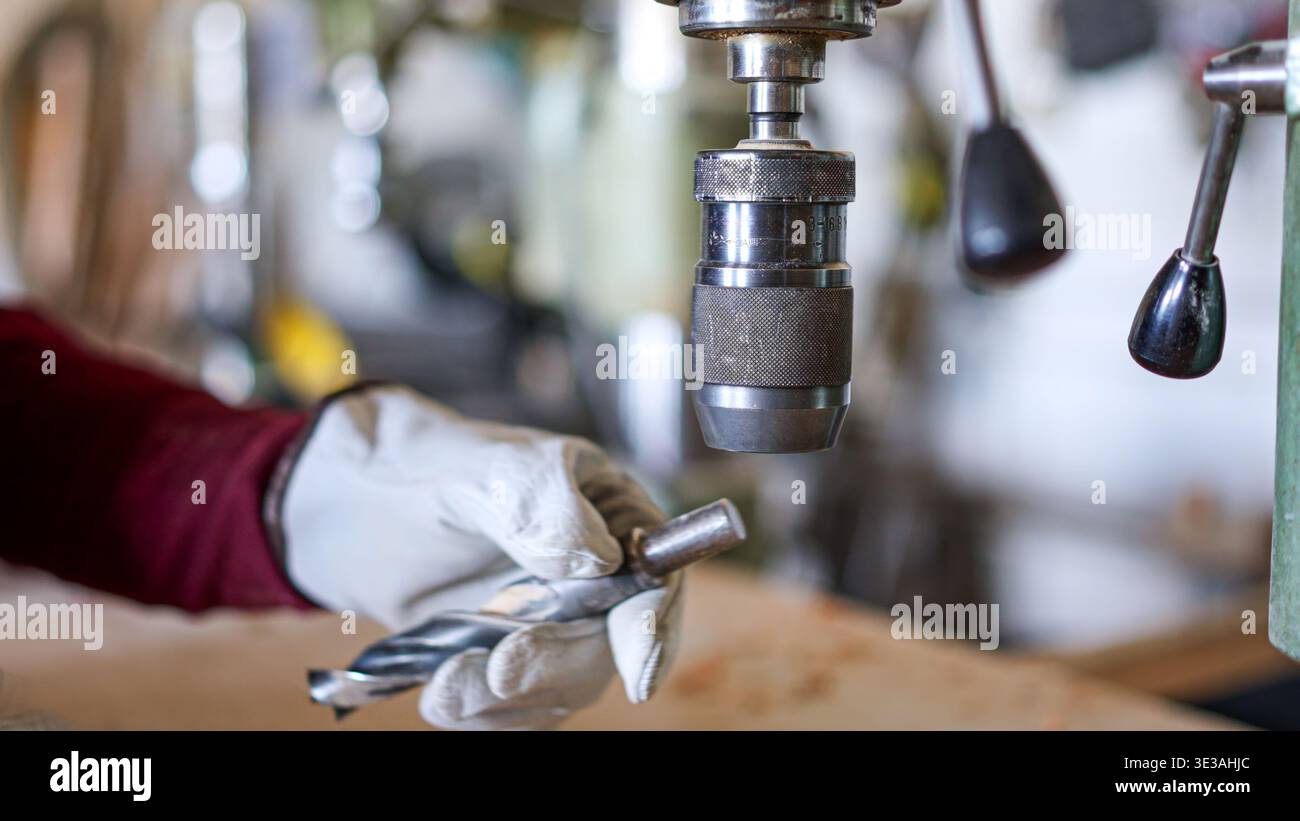 Person changing drill bit on a machine press in workshop Stock Photo