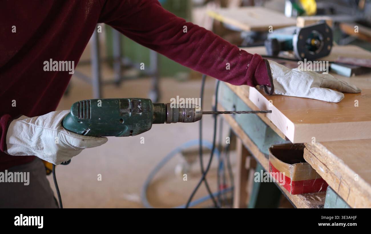 Carpenter drilling wood plank in a workshop Stock Photo