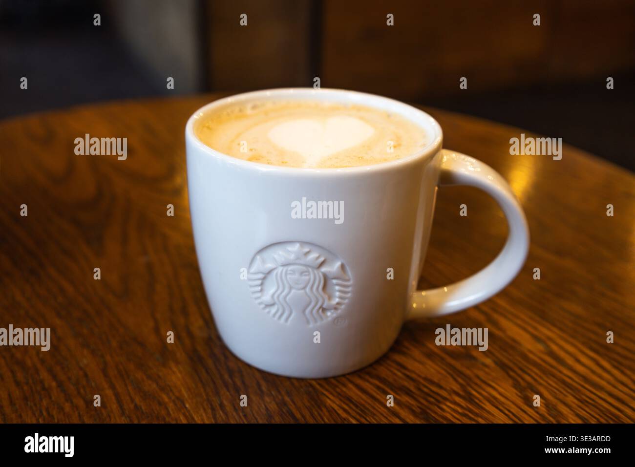 White Starbucks mug with heart latte art on a wooden cafe table. London, UK, 8 July 2023 Stock Photo