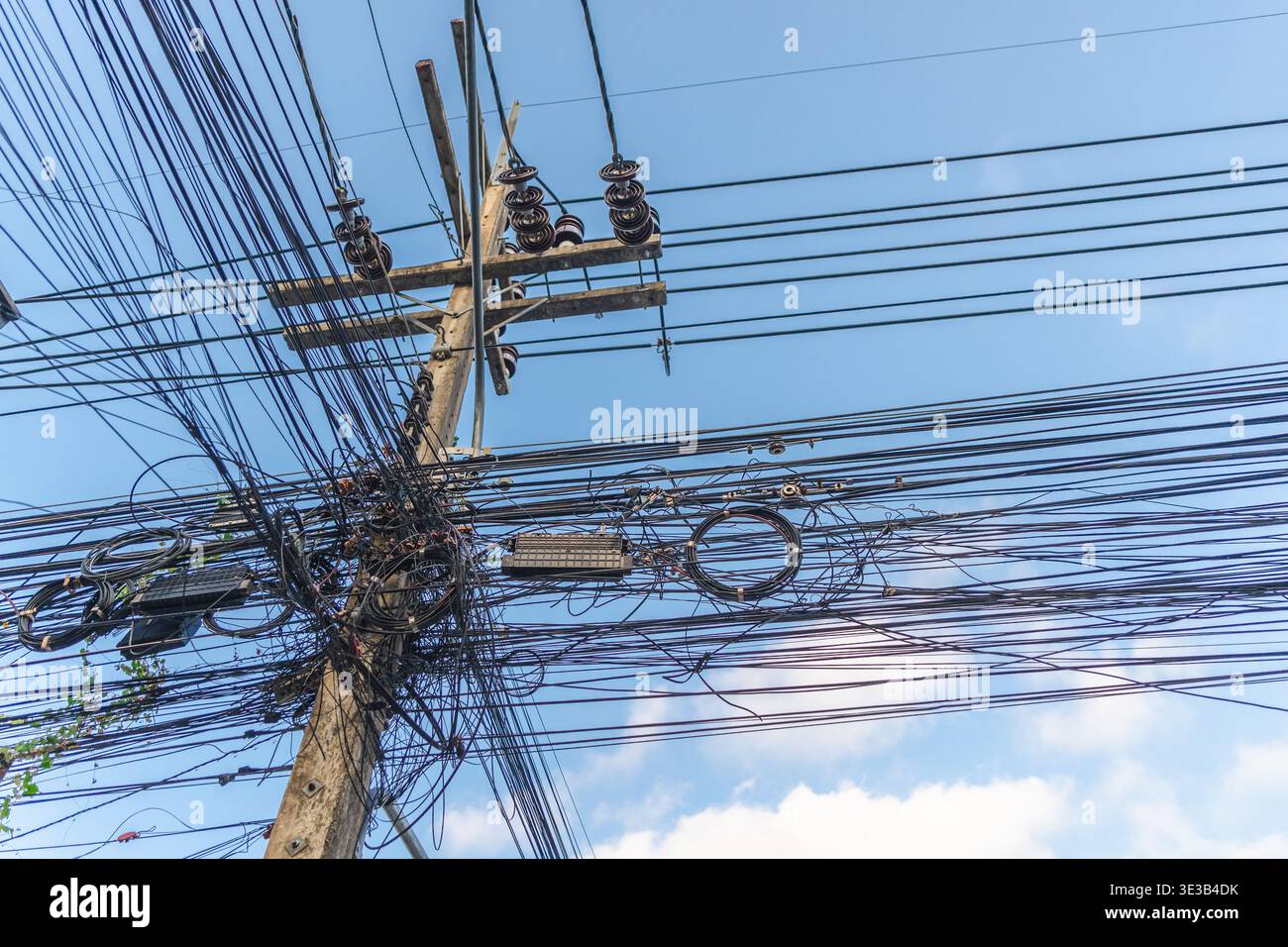 Messy electrical wires on utility pole against blue sky Stock Photo