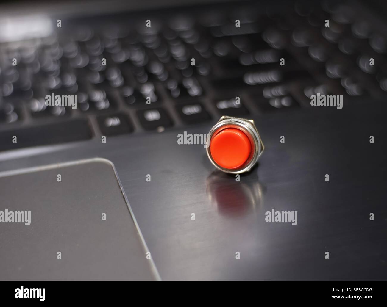 A red push button is placed on a laptop keyboard. Stock Photo