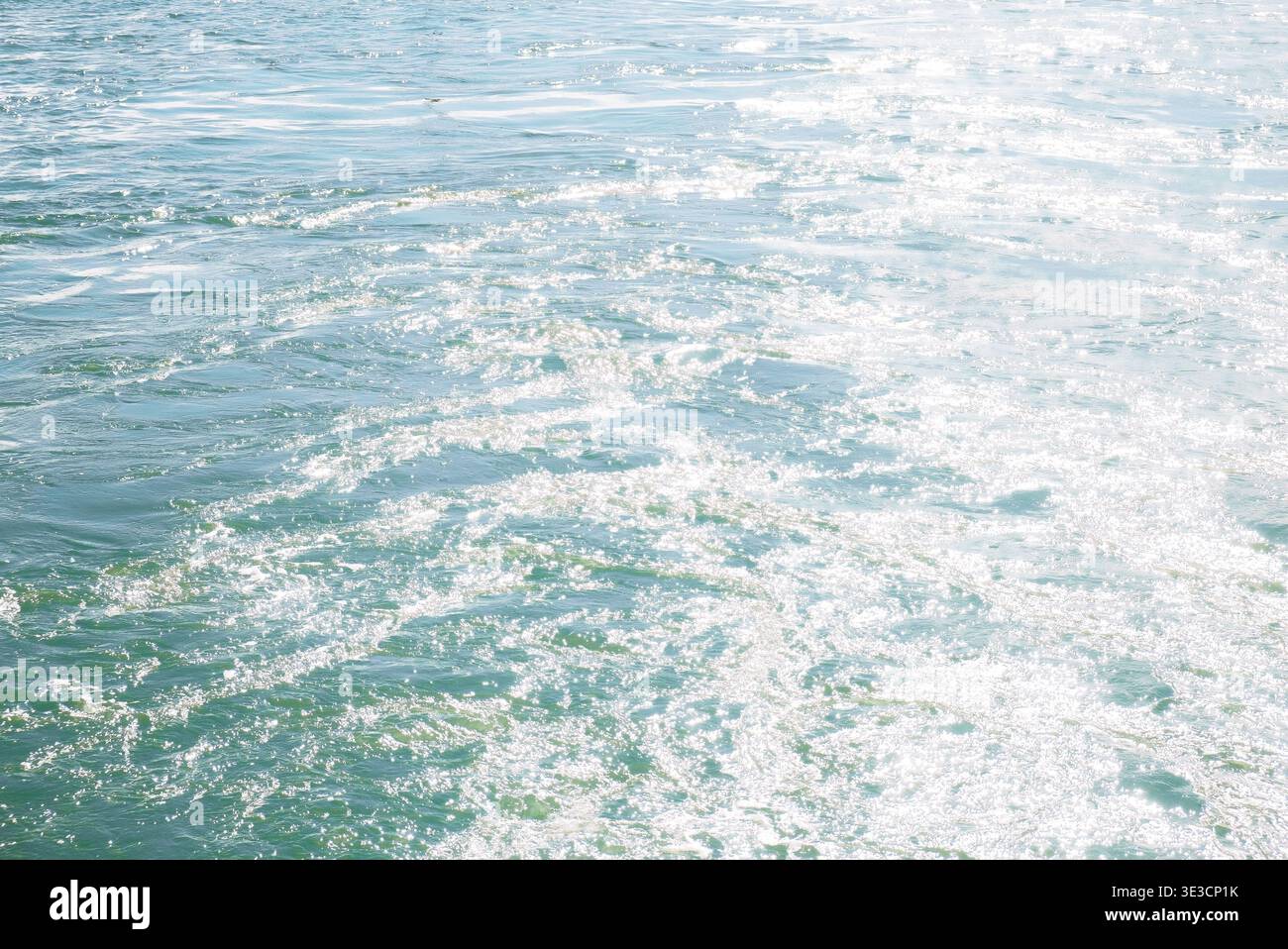Auckland, New Zealand: Sunlight reflects off blue Waitemata Harbour sea water surface during ferry boat transit to Devonport. Stock Photo