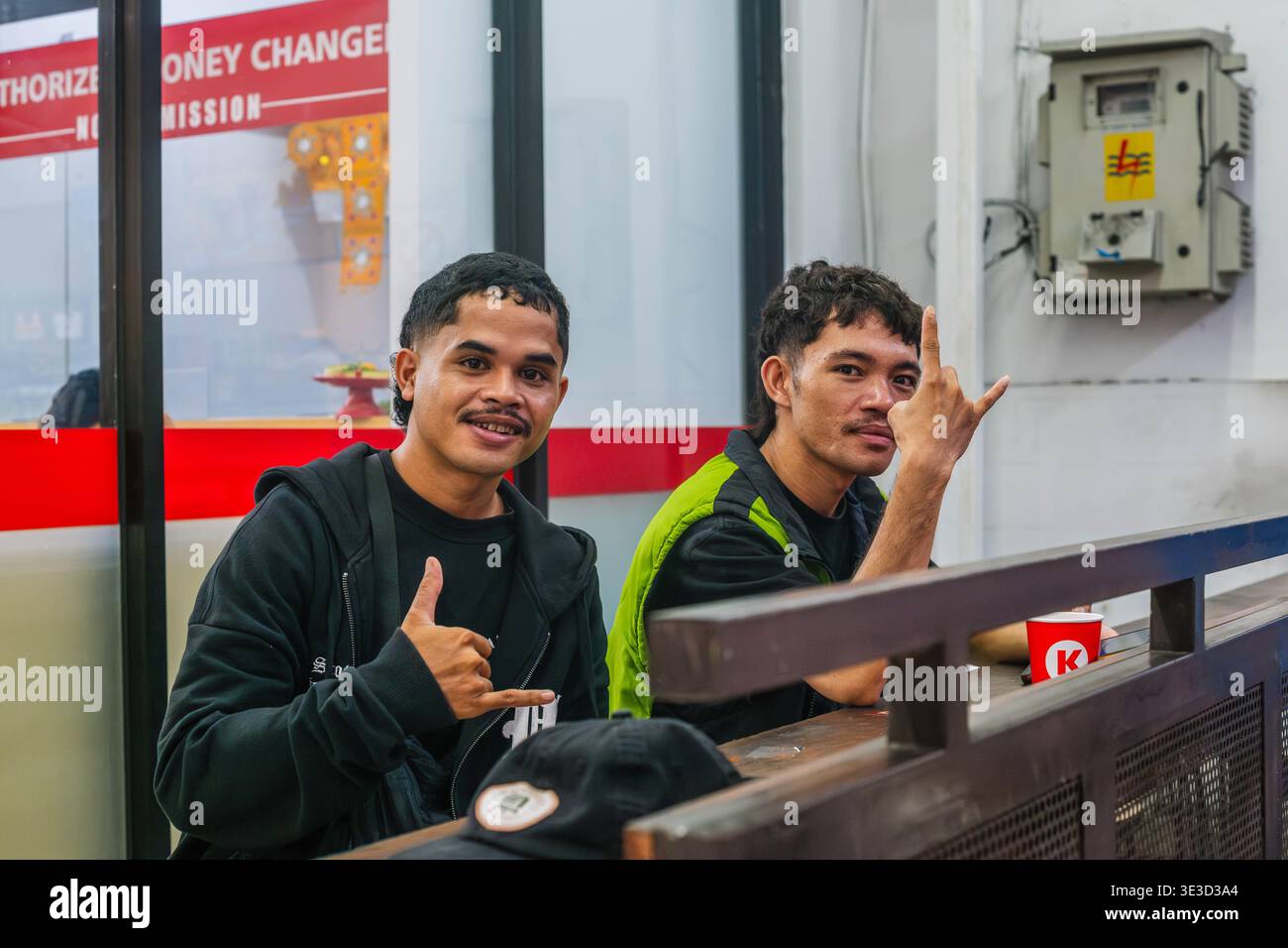 Two Young Men Making Hand Gestures Behind a Counter Stock Photo
