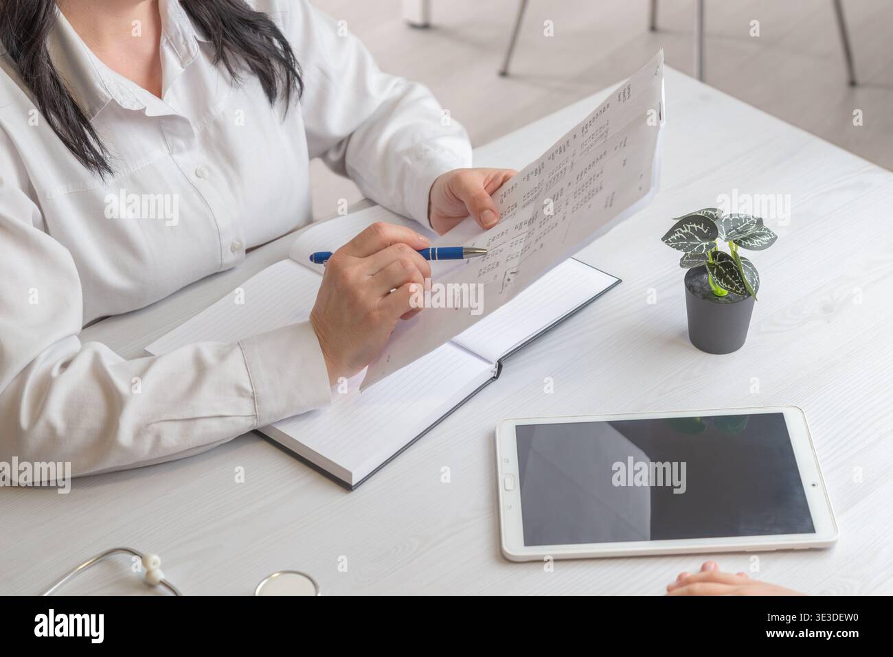 doctor reviewing medical report with tablet on desk representing healthcare analytics and digital medical workflow Stock Photo