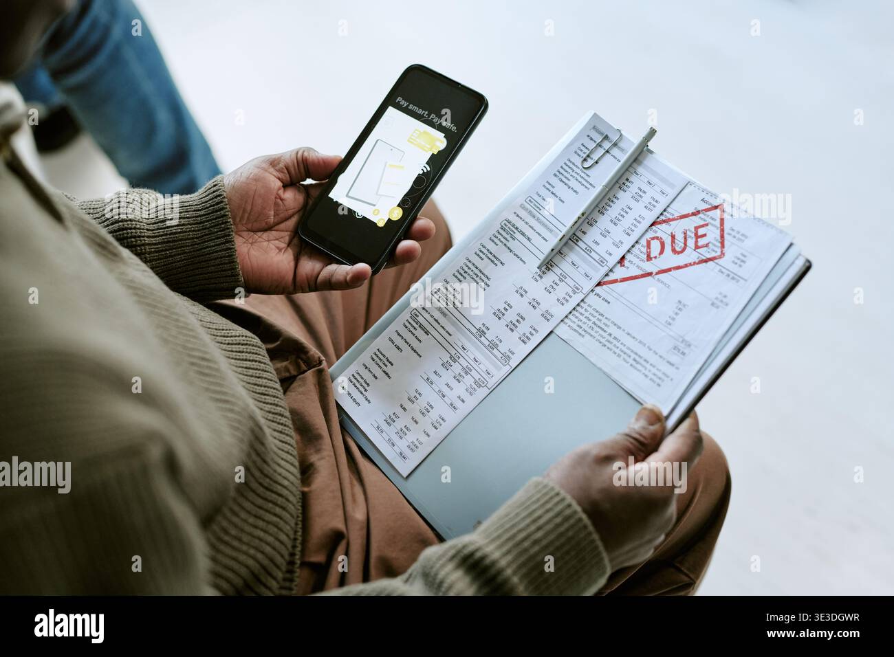 Black Man Using Smartphone While Reviewing Overdue Bank Statement Stock Photo