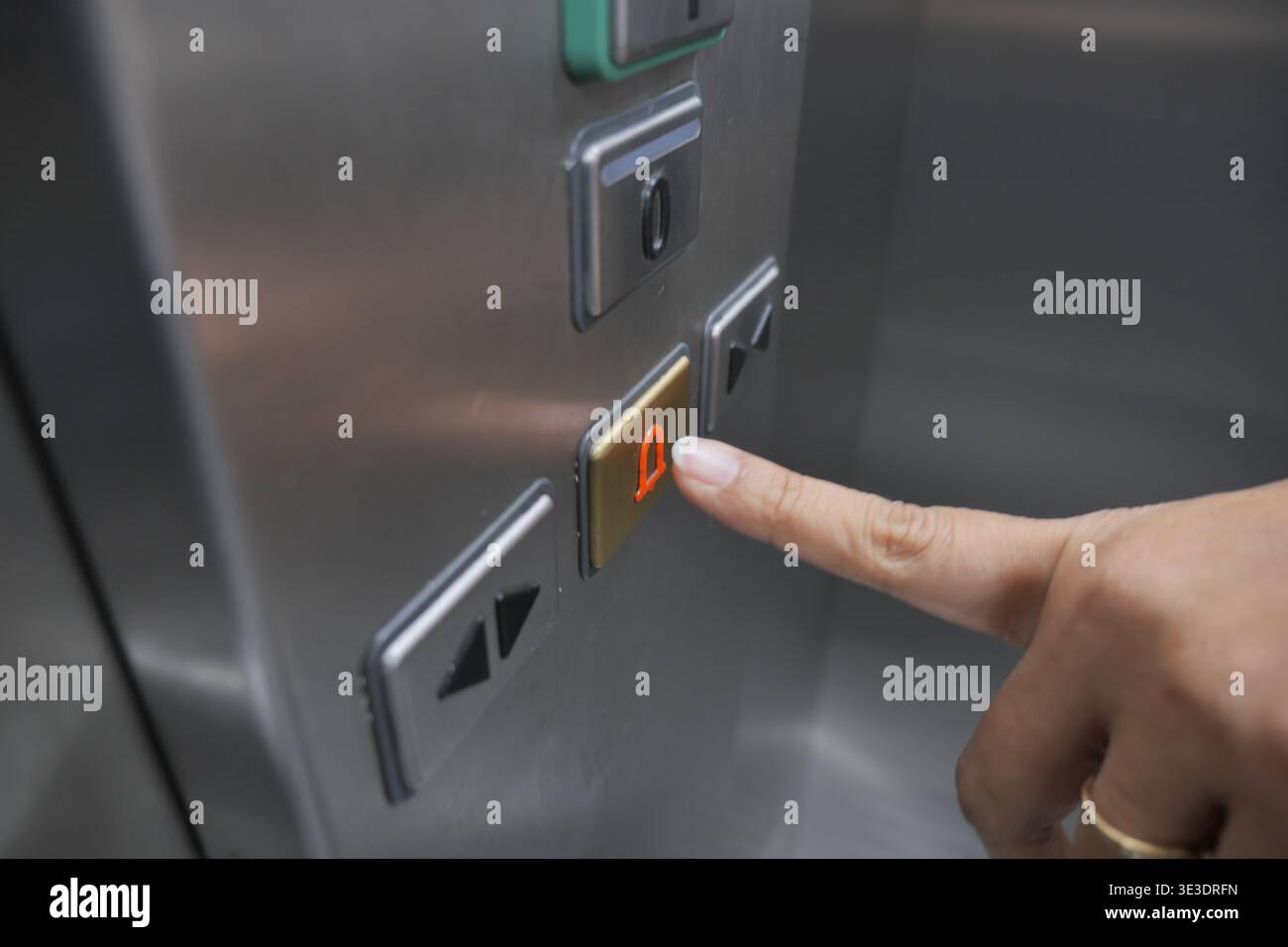 Hand presses elevator button in a building hallway Stock Photo