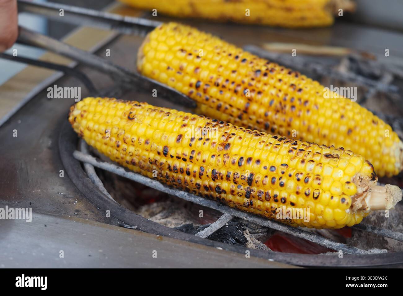 Grilling corn on a barbecue in an outdoor setting Stock Photo