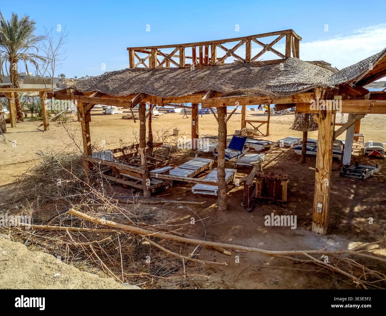 Abandoned beach in Sharm El Sheikh (Egypt). Garbage, broken sunbeds and a dilapidated tent on the sand against the background of the Red Sea - Smartphone Captured Stock Image