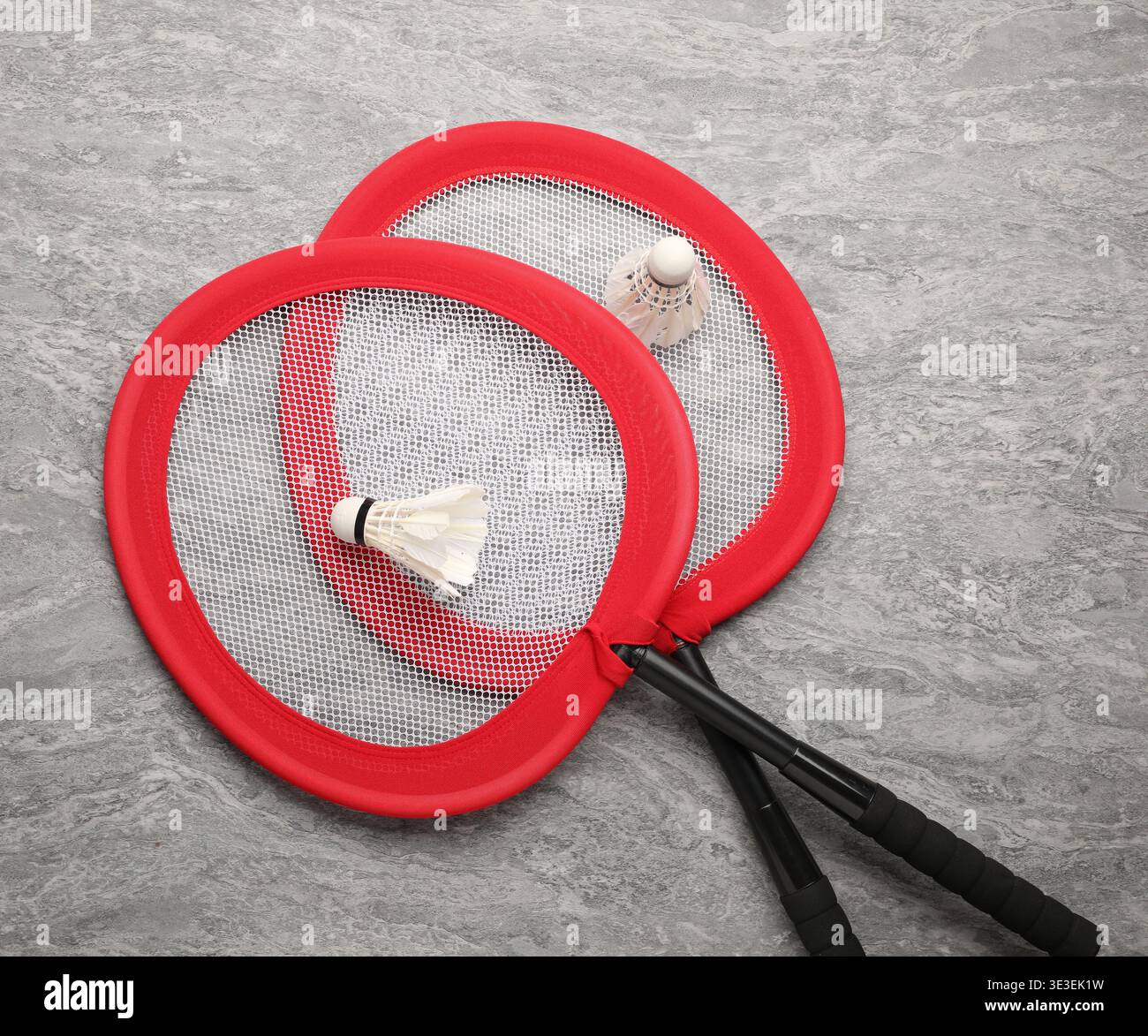 Badminton rackets and shuttlecocks on grey table, top view Stock Photo