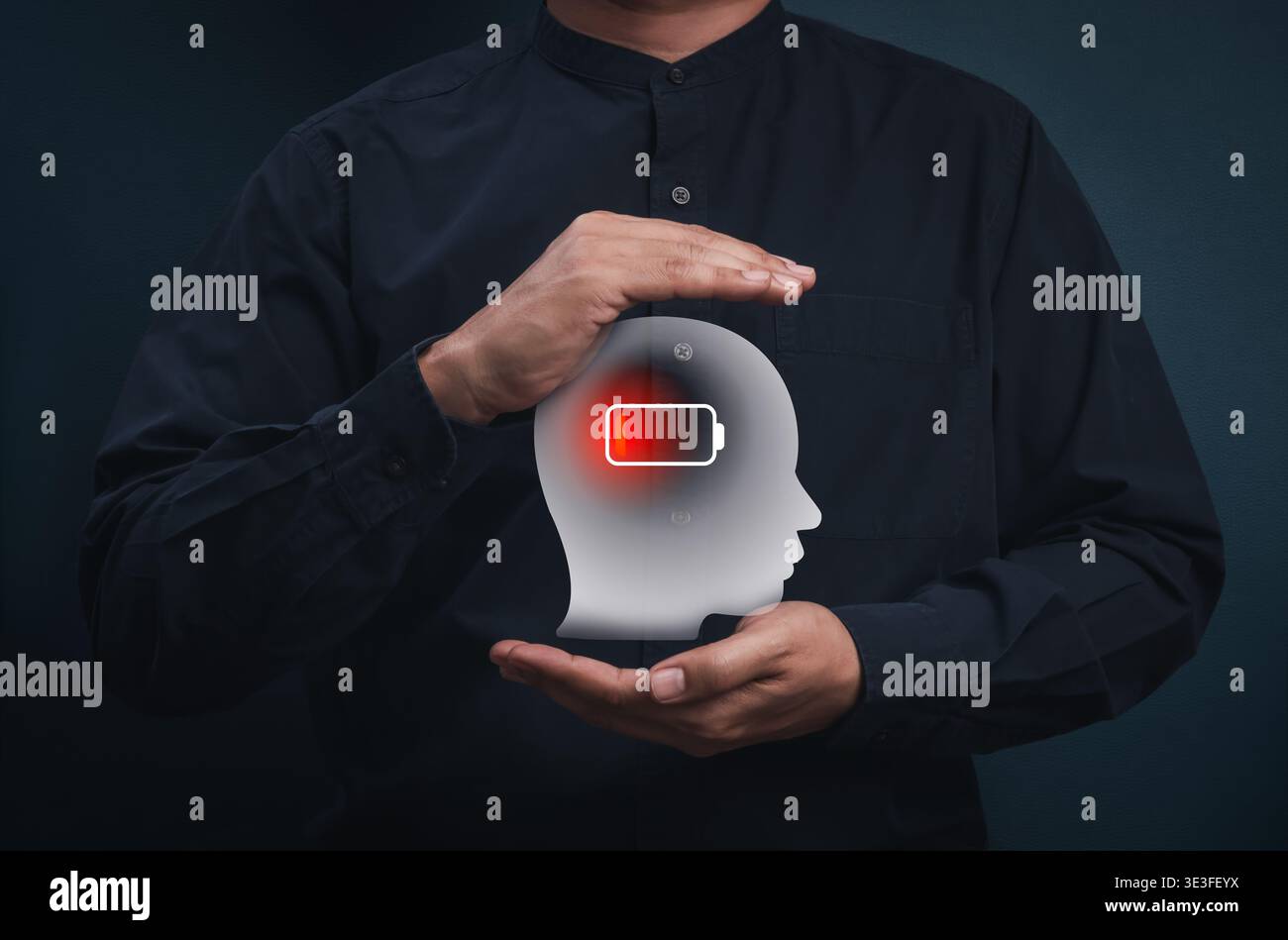 Concept of burnout syndrome and mental exhaustion caused by chronic workplace stress. Human hands holding head silhouette with low battery icon. Fatig Stock Photo