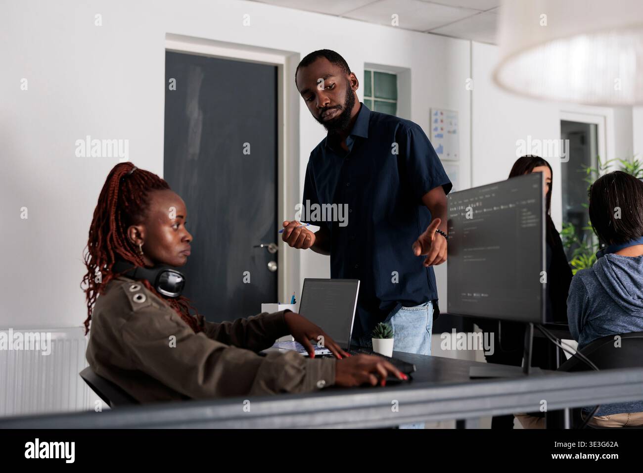 African american software developers discussing about coding script in front of computer, working on server interface development. Programmers doing teamwork to plan html software language. Stock Photo