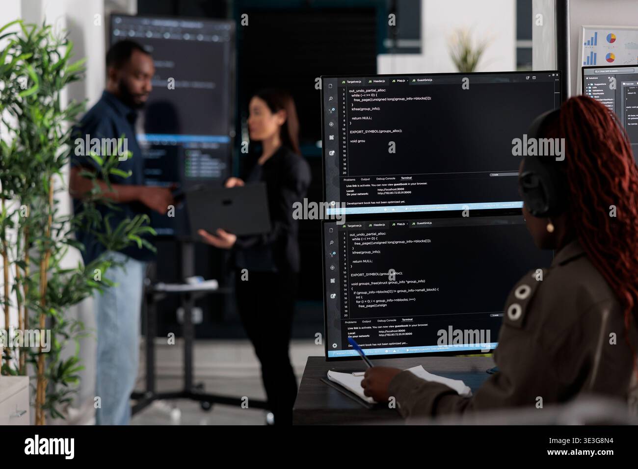 Multi ethnic team of software developers analyzing code on wall screen tv, using digital device and working with artficial intelligence. Programmers parsing cloud computing project with big data. Stock Photo