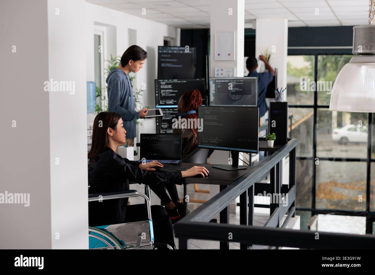 Asian disabled software programmer writing html code in agency big data room, using security system. Engineer with physical disability programming user interface artificial intelligence office. Stock Photo