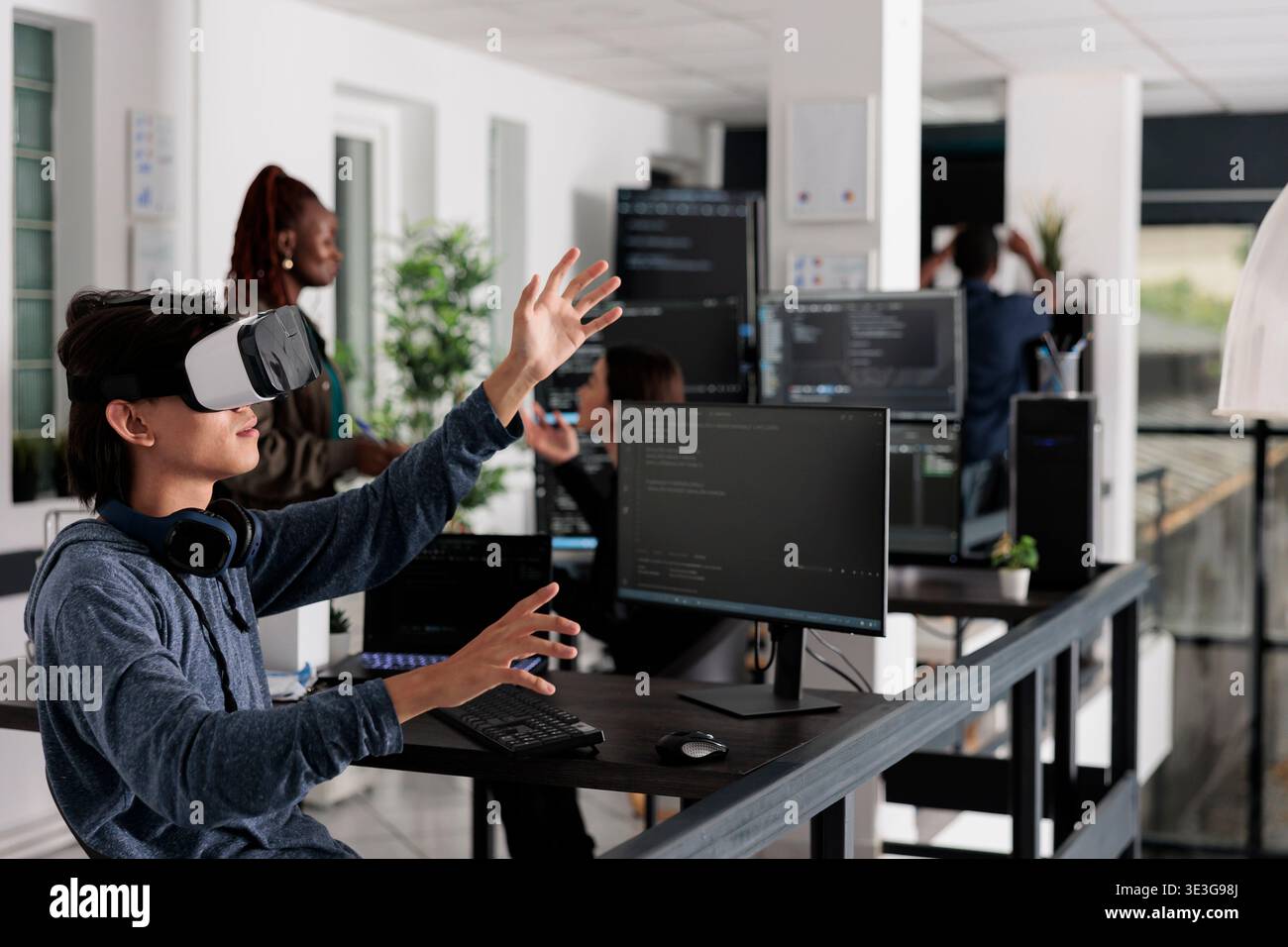 Asian programmer working with virtual reality glasses in it big data office, using vr headset to develop security program. Web developer coding html script with database on computer Stock Photo