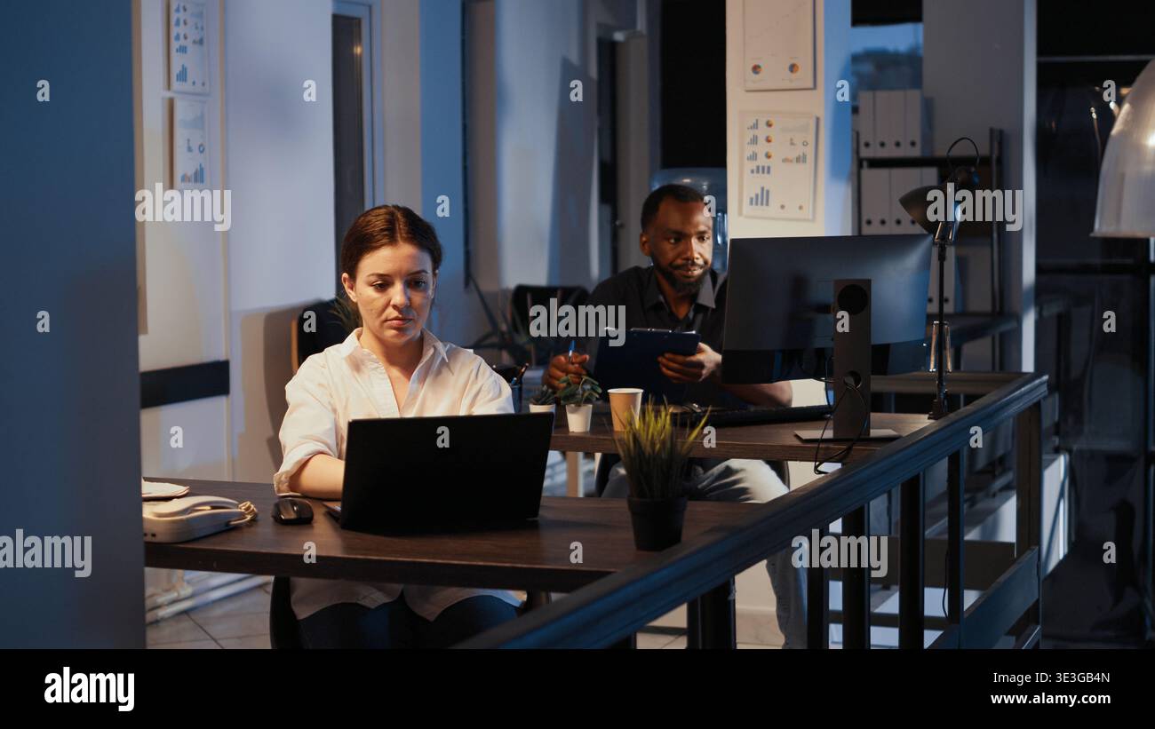 Portrait of confident happy manager working on laptop to plan report, doing research presentation late at night. Using web software to create financial project, app developer. Stock Photo